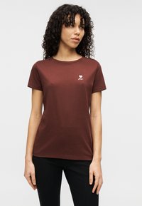 Μπορντό κοντομάνικη κοντομάνικη μπλούζα από βαμβάκι με στρογγυλή λαιμόκοψη και μικρό λευκό γραφικό καρδιά με το κείμενο «Αγάπη» στο στήθος.