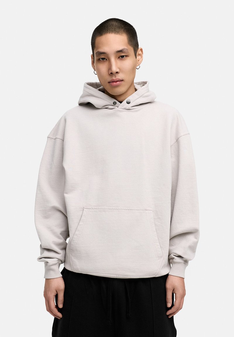 Light gray oversized hoodie made of soft fabric, featuring a front pocket, adjustable drawstring hood, and ribbed cuffs with visible stitching.