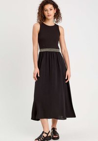 Robe noire sans manches avec un haut côtelé et une jupe fluide et froncée. Présente une taille texturée avec des accents métalliques et un ourlet évasé.