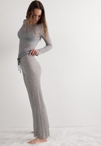 Šedý žebrovaný souprava pohodlného oblečení obsahující dlouhý rukáv a kalhoty se stahovací šňůrkou, zobrazené na neutrálním pozadí.