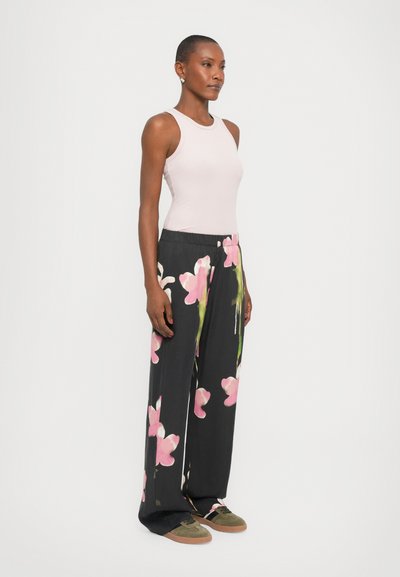 Light pink sleeveless top paired with black wide-leg pants featuring large pink floral prints. Model wears green shoes with brown soles.