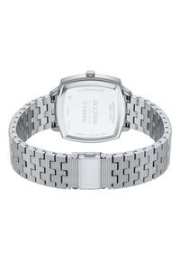 Montre en acier inoxydable argenté avec un boîtier carré, un bracelet texturé et une fermeture. Présente des détails gravés à l'arrière du boîtier.