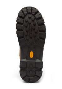 Musta kumikenkien pohja, jossa on syvät urat ja pyöreät pitimet. Varustettu keltaisella Vibram®-logolla. Karhennettu pinta pitoa varten.