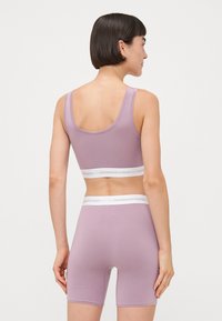 Lilac athletic set featuring a fitted crop top and shorts. Made of soft material, with a white branded elastic band at the waist.