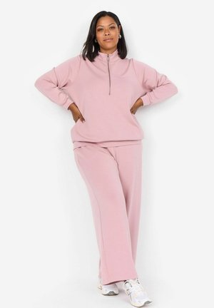 Lichtroze zip-up sweatshirt met lange mouwen, gecombineerd met bijpassende losse sweatpants. Zacht materiaal en ontspannen ontwerp.