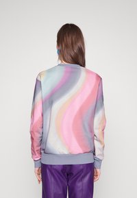 Sudadera con un patrón de olas multicolores en tonos pastel de rosa, púrpura y azul. Presenta un escote redondo y puños acanalados.