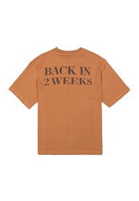 Camiseta de algodón de manga corta y corte oversize en color naranja quemado, con "VOLVER EN 2 SEMANAS" impreso en negro en la parte de atrás. Diseño sencillo y casual.