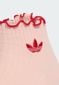 Ροζ ριγωτή κάλτσα με βολάν κόκκινο μανσέτα και κόκκινο κεντημένο λογότυπο που απεικονίζει τρία φύλλα και ρίγες. Απαλή υφή, ελαστικό υλικό.