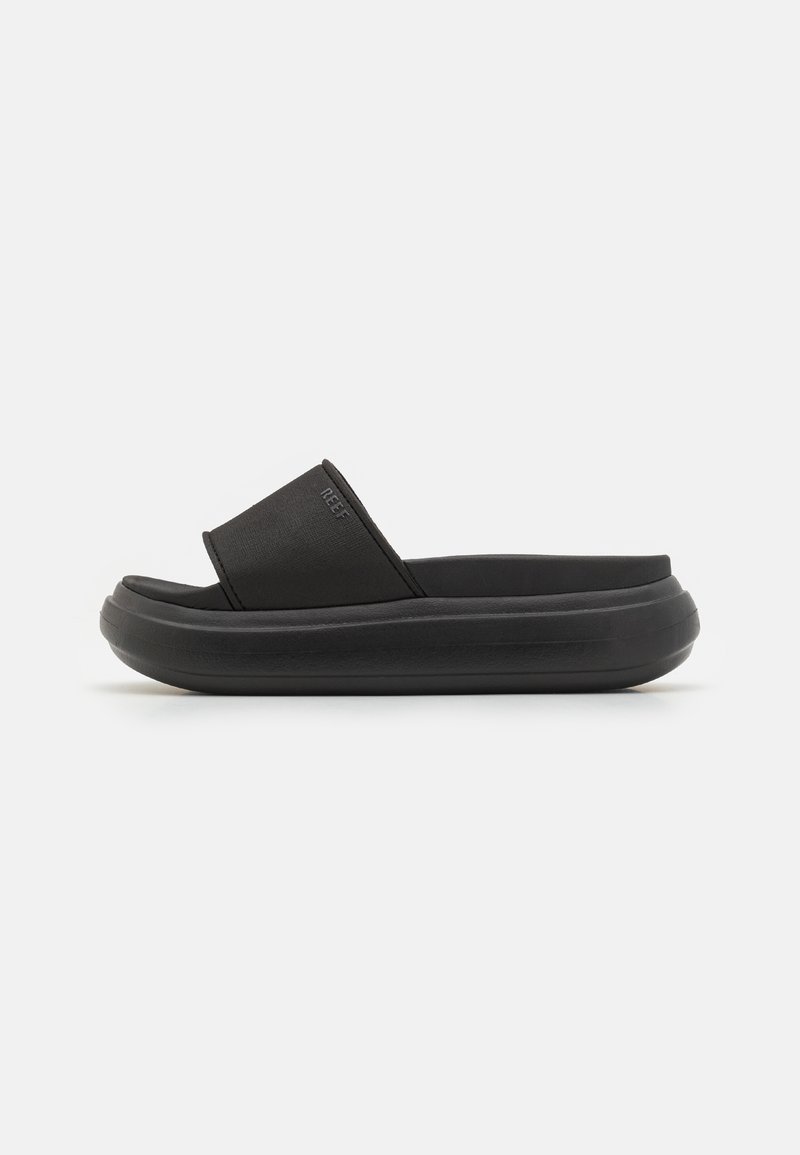 Sandale slide noire avec une semelle épaisse amortie et une large bride sur le dessus, positionnée de côté sur un fond blanc.