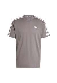 Camiseta deportiva gris de manga corta, hecha de tejido transpirable. Presenta tres rayas blancas en cada hombro y un logo blanco en el pecho.