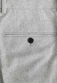 Grauer Stoffhosen-Taschen mit Klappe, versehen mit einem schwarzen Knopfverschluss. Die Textur ist gewebt mit subtilen Sprenkeln, was ein strukturiertes Aussehen verleiht.