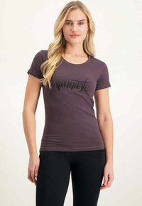 Violetti, istuva t-paita pehmeästä kankaasta, jossa on mustalla kursiivilla painettuna sana "namaste" edessä. Lyhyet hihat, pyöreä kaula-aukko.