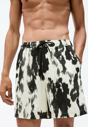 Black-and-white patterned swim shorts featuring an elastic waistband, drawstring closure, and side pockets, made from lightweight fabric.
