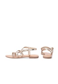 Platte sandalen met metalen gouden banden, voorzien van een kruislings ontwerp en een verstelbare enkelband. Beige zool met minimale textuur.