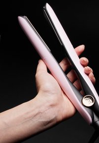 Haarglätter mit einem schwarzen und rosa Design, ausgestattet mit glatten Platten, abgerundeten Kanten und einem runden goldenen Hardware-Detail.