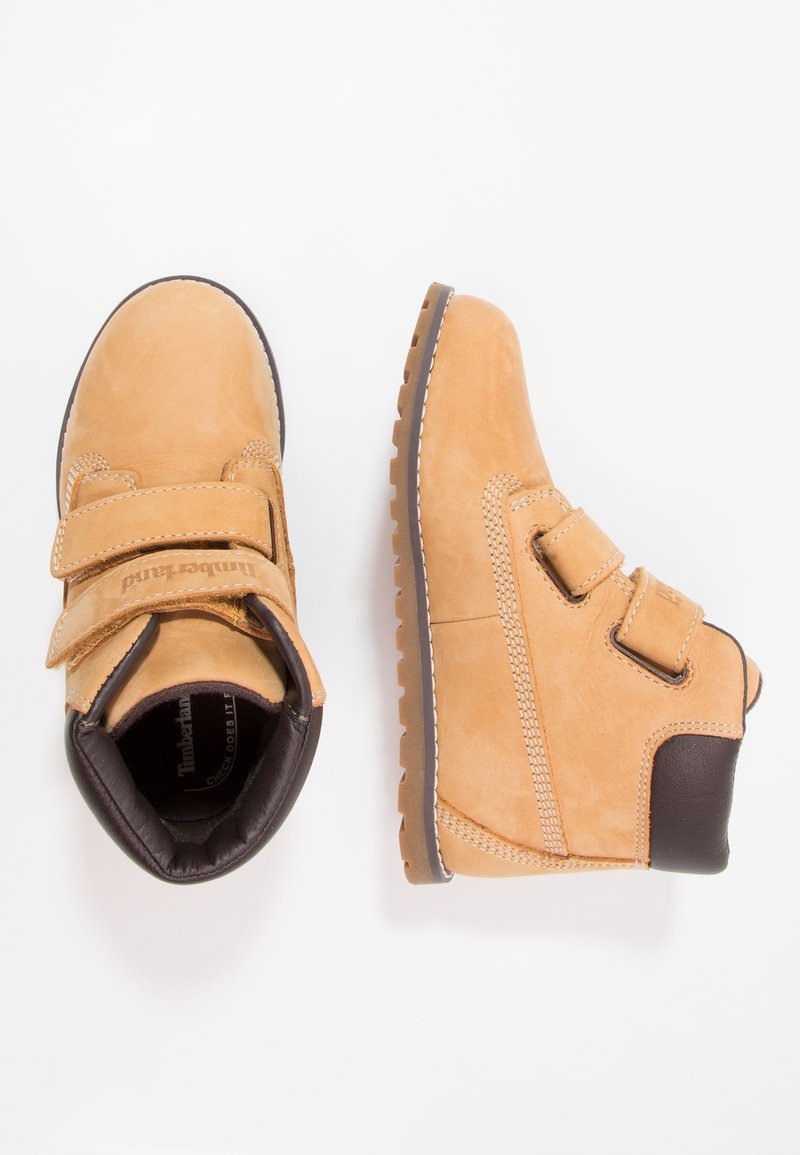 Bottes Timberland pour enfants de couleur tan avec deux sangles Velcro et des cols rembourrés noirs, présentées de dessus et de côté sur fond blanc.