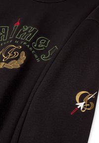 Zwarte sweatshirt met groen en geel grafisch tekst, voorzien van een gouden geborduurd logo en rode details op de mouw. Zacht materiaal, ontwerpen met ronde hals.