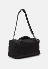 Bolsa de viagem preta feita de um tecido durável, com um bolso lateral de malha texturizada, alças superiores e uma alça ajustável com detalhes do logótipo.