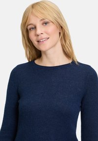 Maglione lavorato a maglia di colore blu navy realizzato in tessuto morbido, con scollo rotondo e maniche lunghe. La texture appare liscia con dettagli minimi.