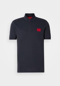 Polo noir à manches courtes avec col, trois boutons et un petit écusson logo rectangulaire rouge sur la poitrine gauche portant l'inscription "HUGO."