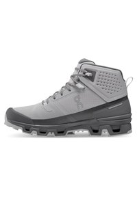 Mid-top gray hiking boot with textured fabric, reinforced toe cap, and lugged outsole for traction. Features quick-lace system and branding.