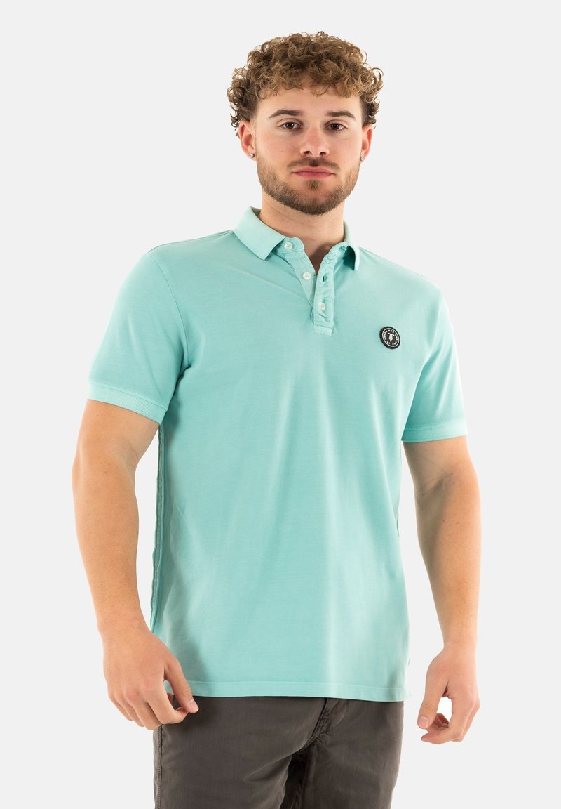 Polo shirt bleu clair à manches courtes avec un col boutonné et un patch logo sur le côté gauche. Fabriqué en tissu de coton doux.