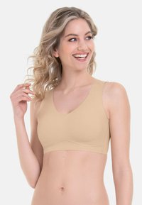 Beige, nahtloser, drahtloser BH mit V-Ausschnitt. Glattes, flexibles Material schmiegt sich an den Körper. Breite Träger für zusätzlichen Komfort und Unterstützung.