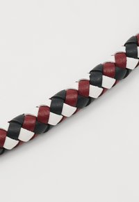 Correa de cuero trenzado en rojo, negro y blanco, que presenta un diseño trenzado con una textura suave y un ancho uniforme en toda su extensión.