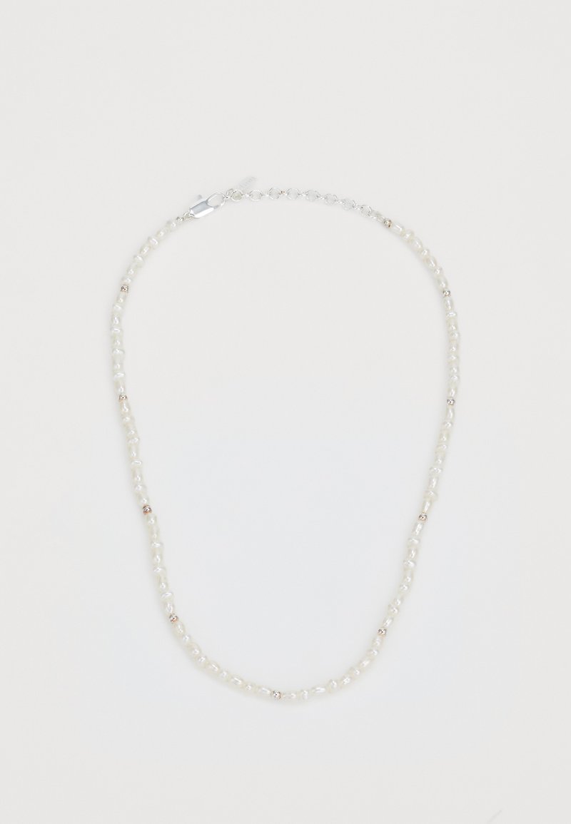 Collana di perle con perle bianche irregolari intervallate da piccoli dettagli metallici. Chiusura sicura e catena regolabile.