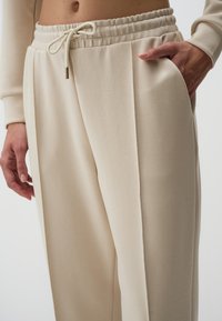 Relaxed-fit beige sweatpants van zacht materiaal, met een elastische tailleband met een trekkoord en zijzakken.