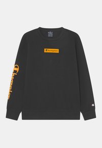 Sudadera negra de manga larga con el logo naranja "Champion" en el pecho y en la manga izquierda, y pequeño logo de Champion bordado en el puño derecho.