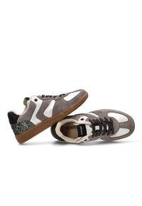 Zapatillas de ante gris con acentos blancos, cordones negros, suela de goma y un detalle de talón brillante en verde. Forro de felpa visible en el collar.