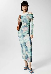 Off-shoulder blomsterkjole i gennemsigtigt blågrønt stof, med en figursyet silhuet, lange ærmer og en midt-længde kant.