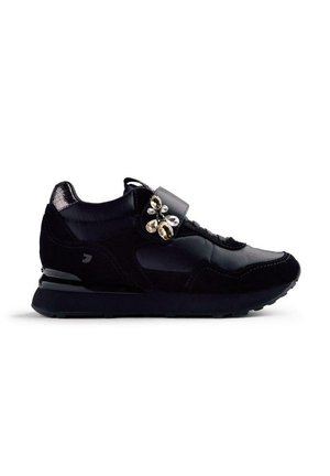 Chaussure de sport noire en matériaux mixtes, avec un embout brillant, du daim texturé, une sangle ajustable ornée de gemmes décoratives et une semelle en caoutchouc.