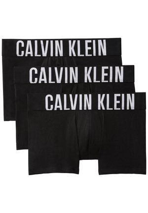 Trois boxers noirs Calvin Klein empilés, chacun avec une large ceinture affichant le nom de la marque en grandes lettres blanches.