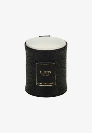 Portacandele nero con texture, etichetta con accento dorato che recita "GUESS VETYVER HOME COLLECTION." Include una candela bianca all'interno.