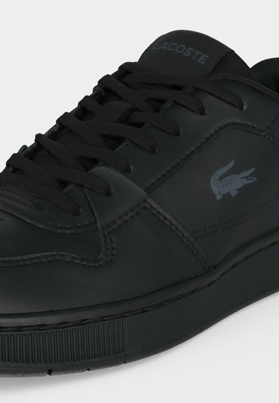 Черна кожена маратонка Lacoste с черни връзки и логото на крокодил на марката отстрани и текст "Lacoste" на езица.