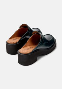 Zoccoli in pelle nera con platform e schiena aperta, caratterizzati da una punta arrotondata, una finitura liscia e una soletta di contrasto color tan con logo inciso.
