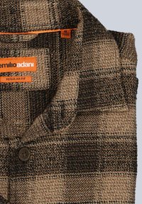 Brown and beige plaid shirt, made of textured fabric, featuring a folded collar, button detail, and brand label with orange accents.