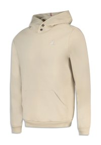 Sudadera beige hecha de material suave, con un bolsillo canguro, un cuello alto con botones y un logo bordado en el pecho.