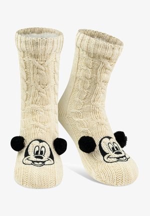 Knit socks in cream with a cable pattern; features a black Mickey Mouse face and two black pom-poms on the toes. Soft, textured material.