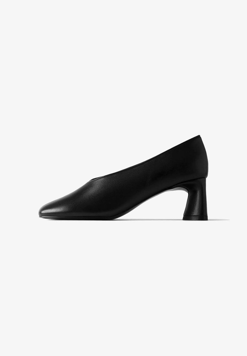 Chaussure basse en cuir noir avec bout arrondi et talon bloc, vue de côté sur fond blanc.