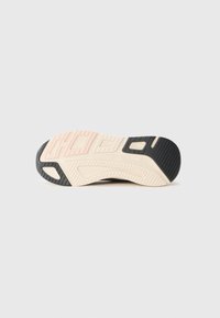 Semelle de sneaker noire et crème en caoutchouc texturé, de forme arrondie, avec un accent rose près du talon ; présente des motifs de traction en forme de canaux.
