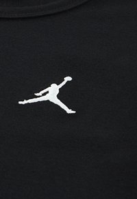 Fekete szövet póló, fehér hímzett Jumpman logóval. Az anyag sima tapintású, a dizájn klasszikus kerek nyakkivágással rendelkezik.