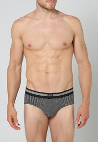 Schwarz-weiß gestreifte Unterhosen mit einem weichen, elastischen Bund. Der Stoff wirkt glatt, hat eine enge Passform und ein konturiertes Vorderdesign.