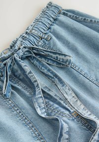 Ljusblå denimshorts med elastisk midja och knytning fram, med blekta detaljer och synliga sömmar.