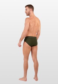 Zelené plavky s proužky s jednolitou texturou a kontrastním pasem. Model je zobrazen zezadu, bosý, na neutrálním pozadí.