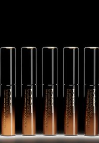Cinque tubetti di correttore MAC Studio Radiance 24HR Luminous Lift, con tappi neri e diverse tonalità di liquido in bottiglie cilindriche.