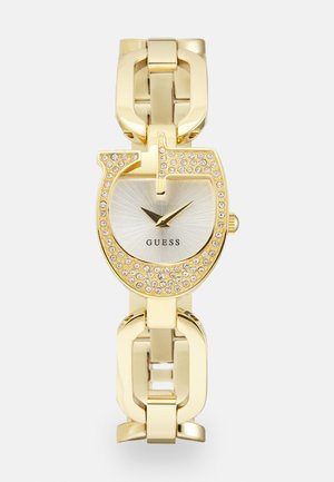 Montre en métal doré avec un cadran rond, un cadran argenté, des index d'heure minimalistes et des rhinestones intégrés dans un bracelet au design unique.