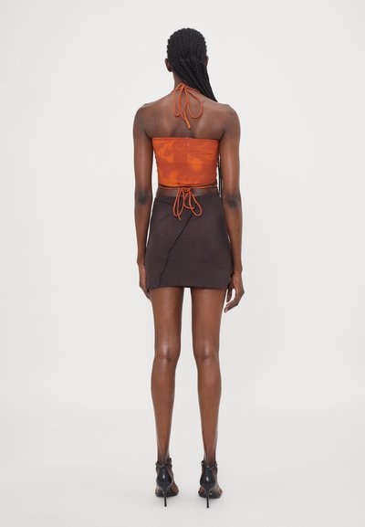 Orange halter crop top with a fitted design, gathering details, paired with a brown mini skirt featuring a diagonal wrap style and smooth texture.